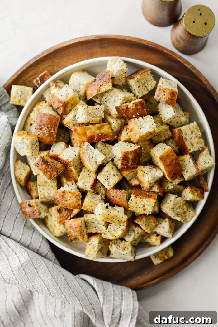 Golden Crispy Homemade Croutons 9 A bowl of fresh homemade croutons with a rustic wooden spoon on a patterned surface