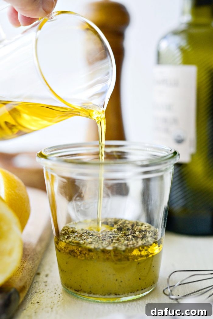 Pouring olive oil into the jar to complete the Greek dressing ingredients