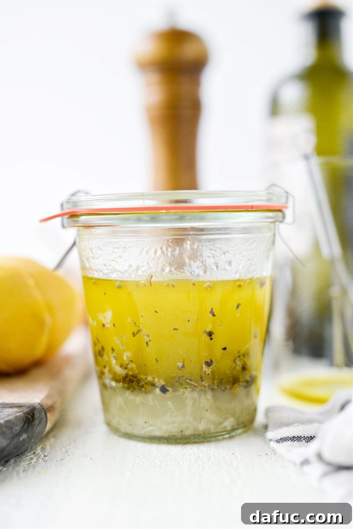 Homemade Greek Dressing in a clear jar, showcasing its fresh ingredients