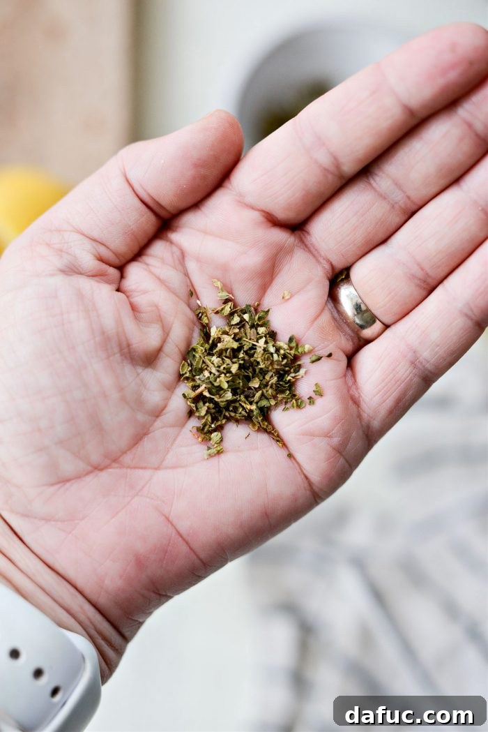 Dried oregano being crushed in a person's palm to release flavor