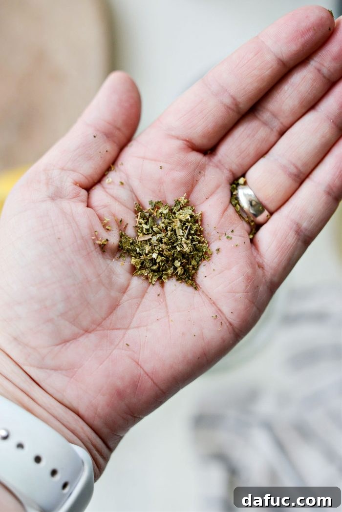 Finely crushed oregano in a palm, ready to be added to the dressing