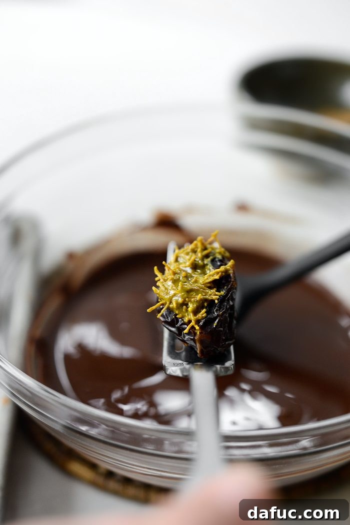 A filled date on a fork being dipped into melted chocolate