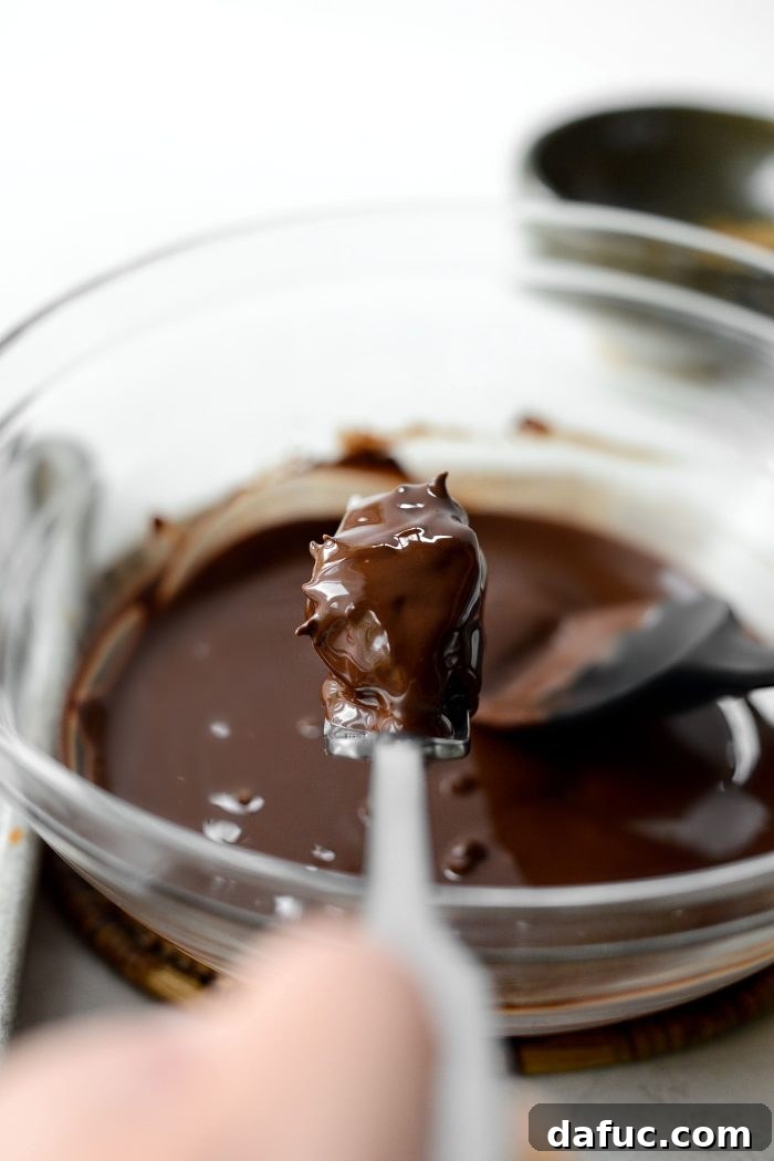 A filled date completely covered in melted chocolate on a fork