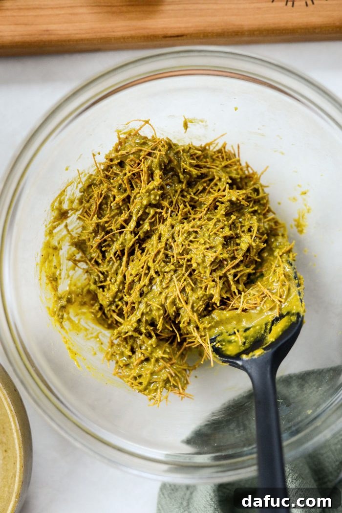 Mixing pistachio cream and kataifi together in a bowl