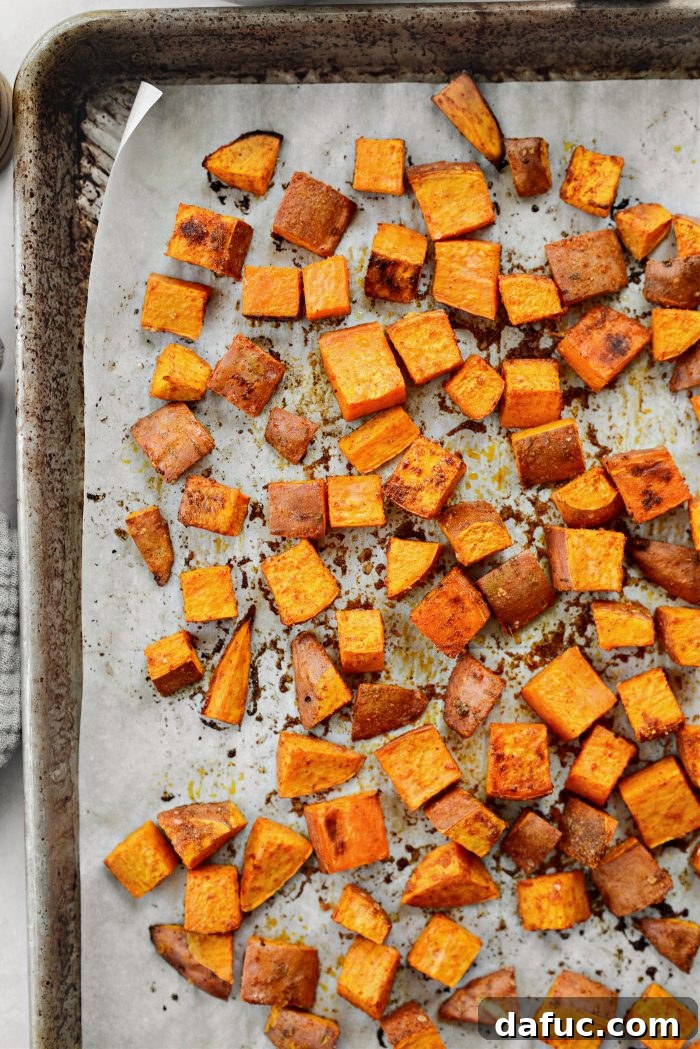 Close-up of golden-brown roasted sweet potato cubes on a baking sheet.
