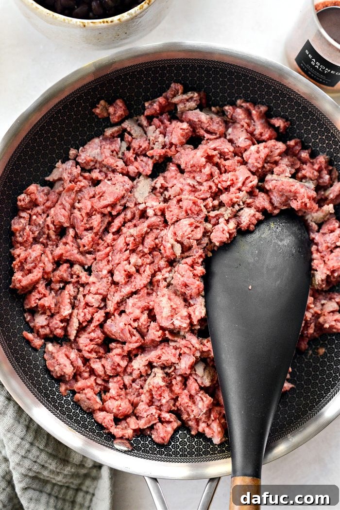 Ground beef cooking in a skillet on the stovetop.