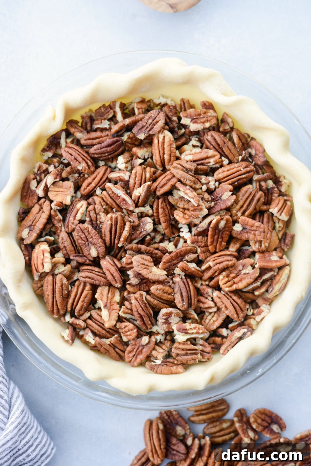Irresistible Classic Pecan Pie 14 Adding chopped and whole pecans to the chilled pie crust.