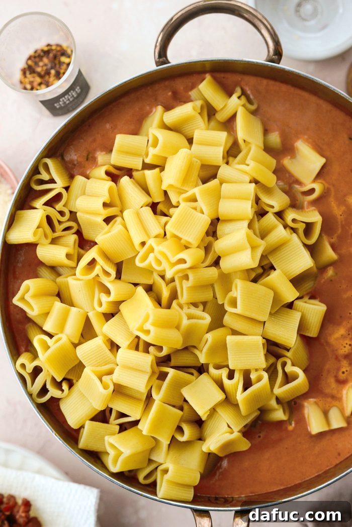 Creamy Blush Pasta 21 Adding drained pasta and reserved pasta water to the sauce