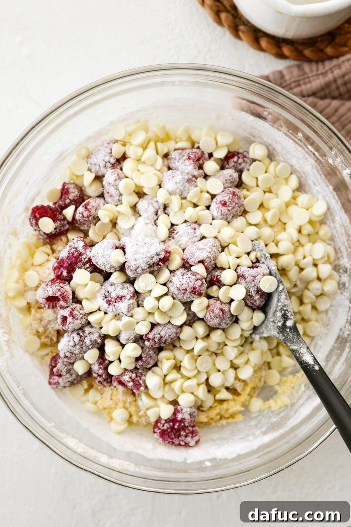 Adding raspberries and white chocolate chips to muffin batter