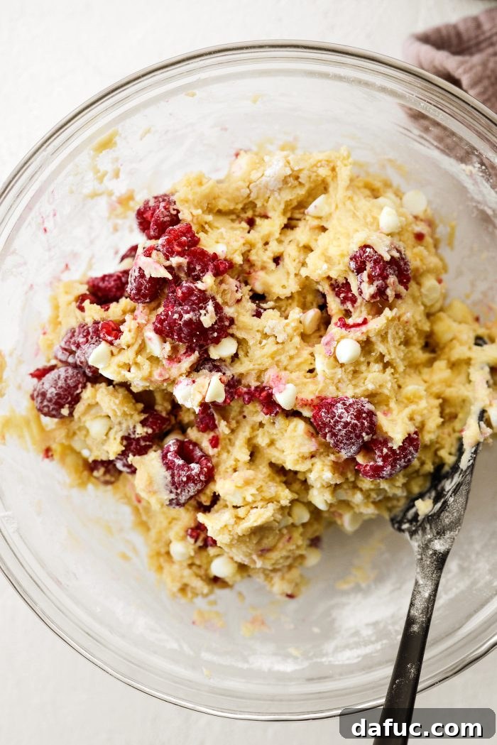Gently folding raspberries and white chocolate into muffin batter