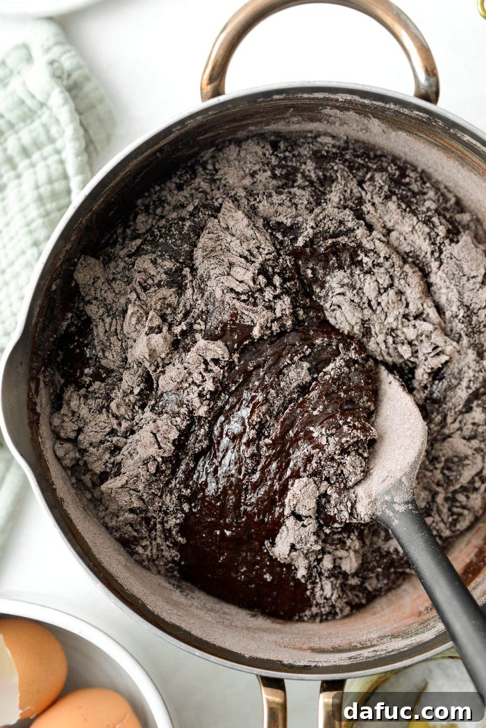 Gently stirring the flour and cocoa mixture into the glossy chocolate batter
