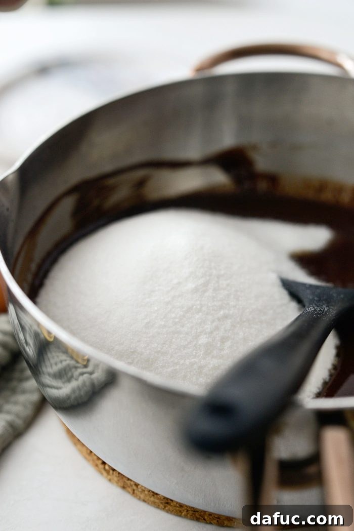 Adding granulated sugar to the warm chocolate and butter mixture
