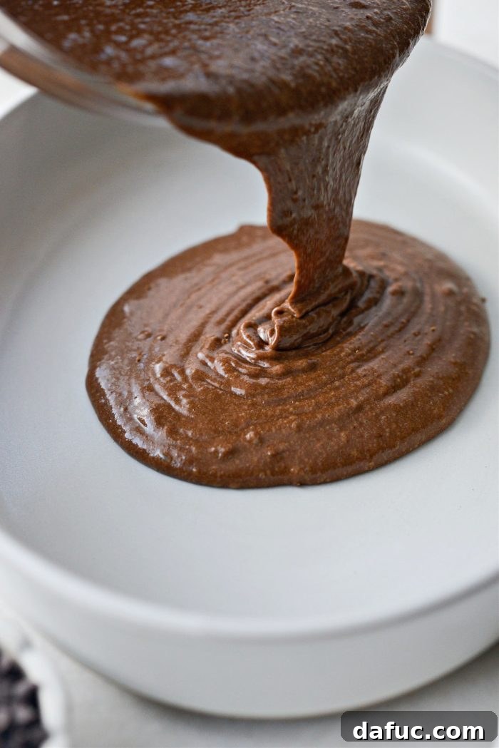 Pouring chocolate cake batter into a baking dish