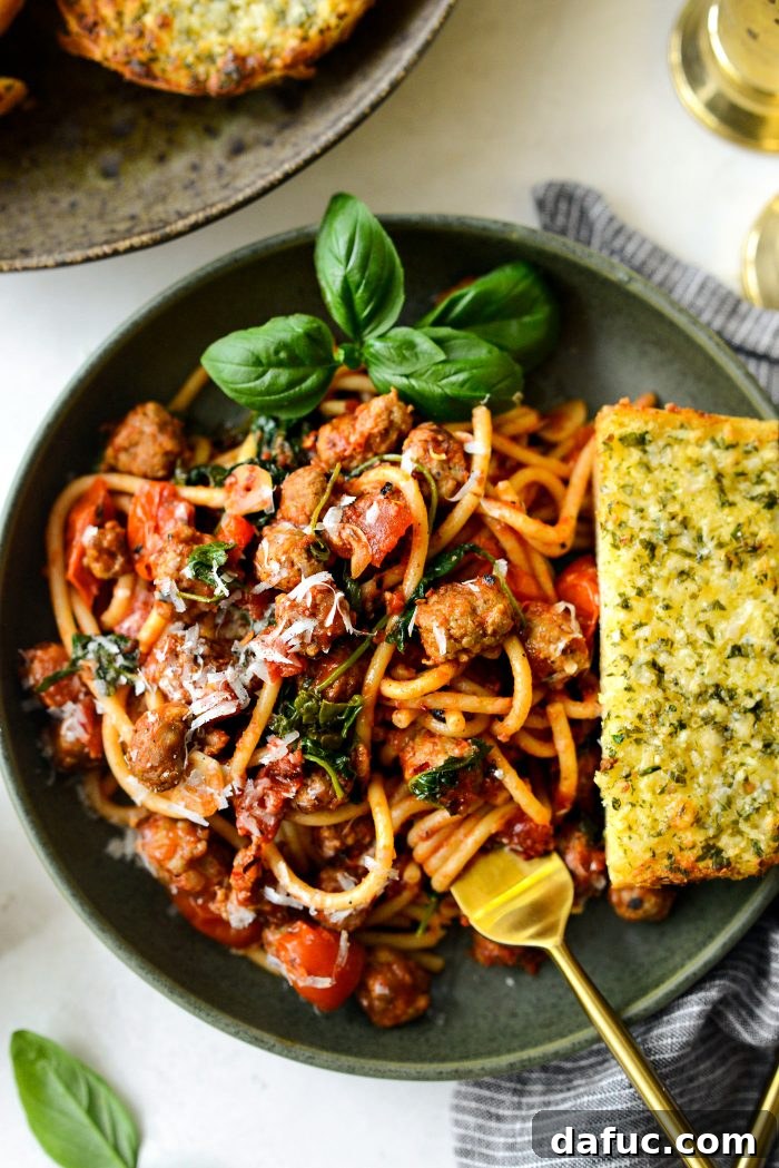 Hearty Sausage and Kale Pasta with Burst Tomatoes 3 Italian Sausage Tomato Kale Pasta, cooked and ready to serve in a deep skillet, showcasing rich colors and textures.