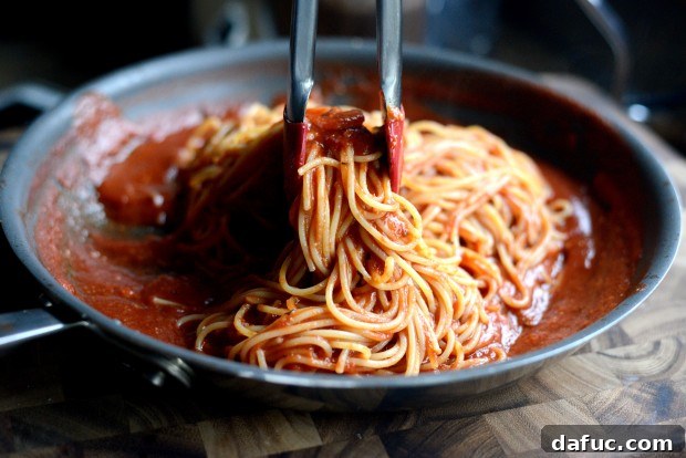 Adding cooked spaghetti to remaining marinara sauce