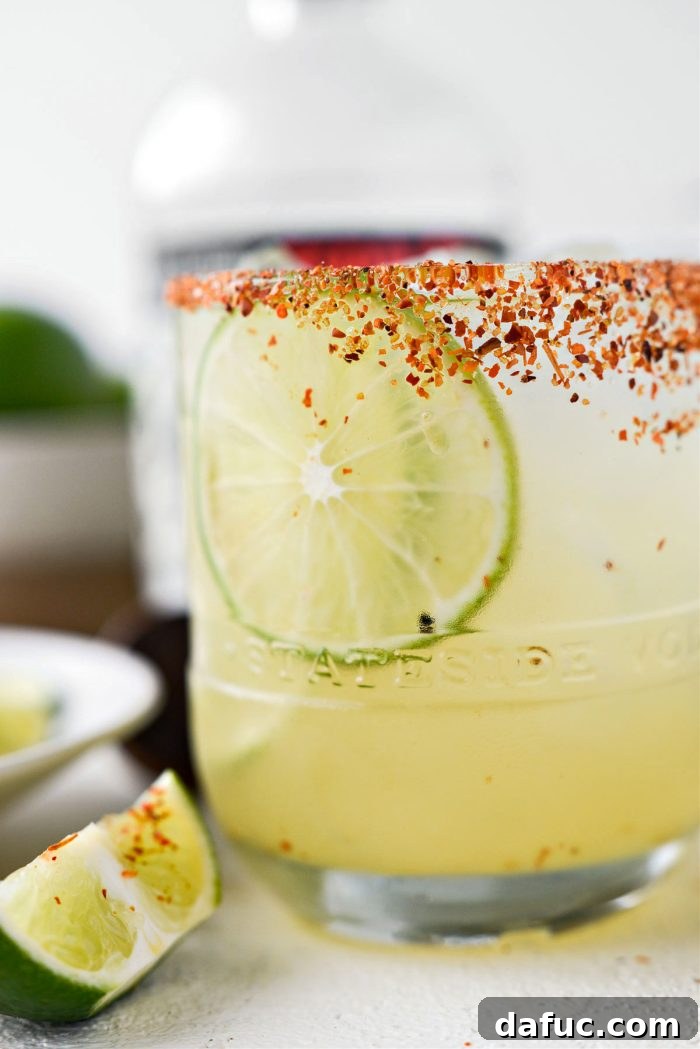 Overhead shot of two Honey Lime Margaritas on a table with a plate of sliced limes.