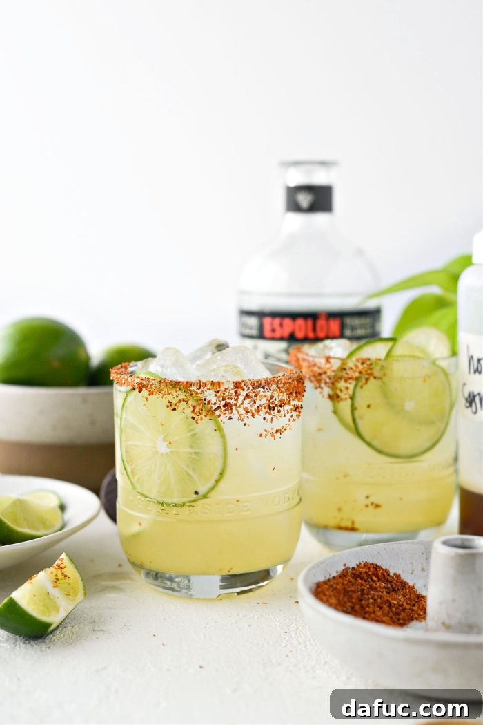 Close-up of two Honey Lime Margaritas garnished with lime wheels.