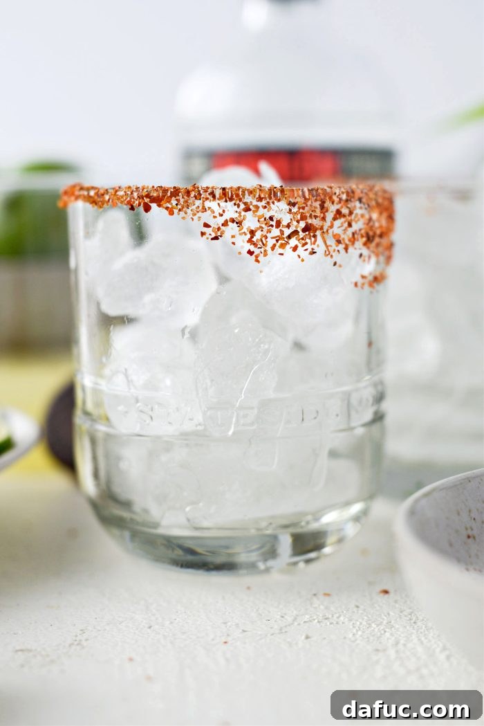 Two cocktail glasses being filled with ice cubes.