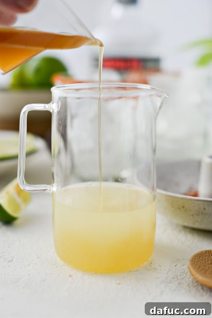 A small jug containing a mixture of lime juice and honey syrup.
