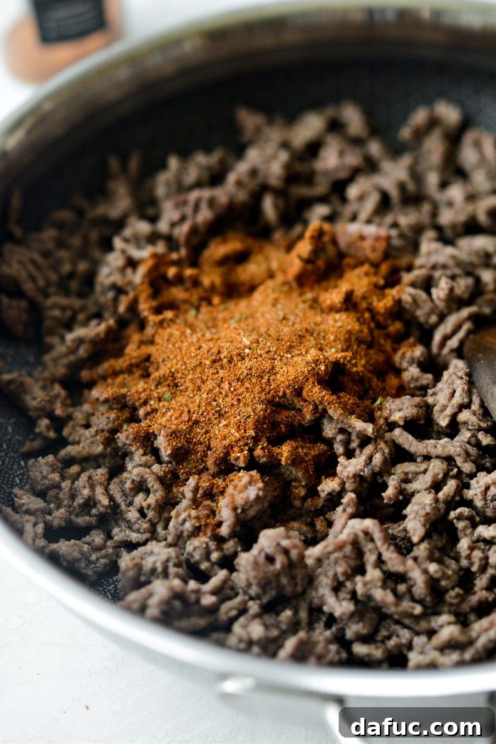 Loaded Chopped Taco Salad 6 Cooked ground beef being seasoned with taco seasoning in a skillet.