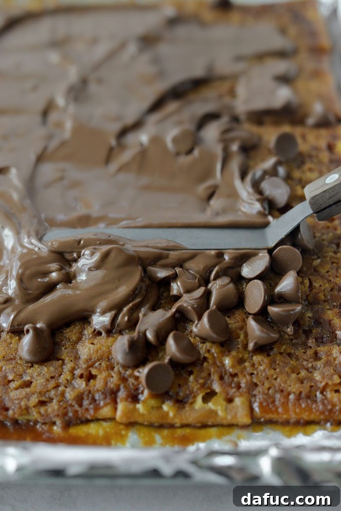 Salty Sweet Toffee Crunch 11 A spatula spreading the melted chocolate evenly across the toffee layer.