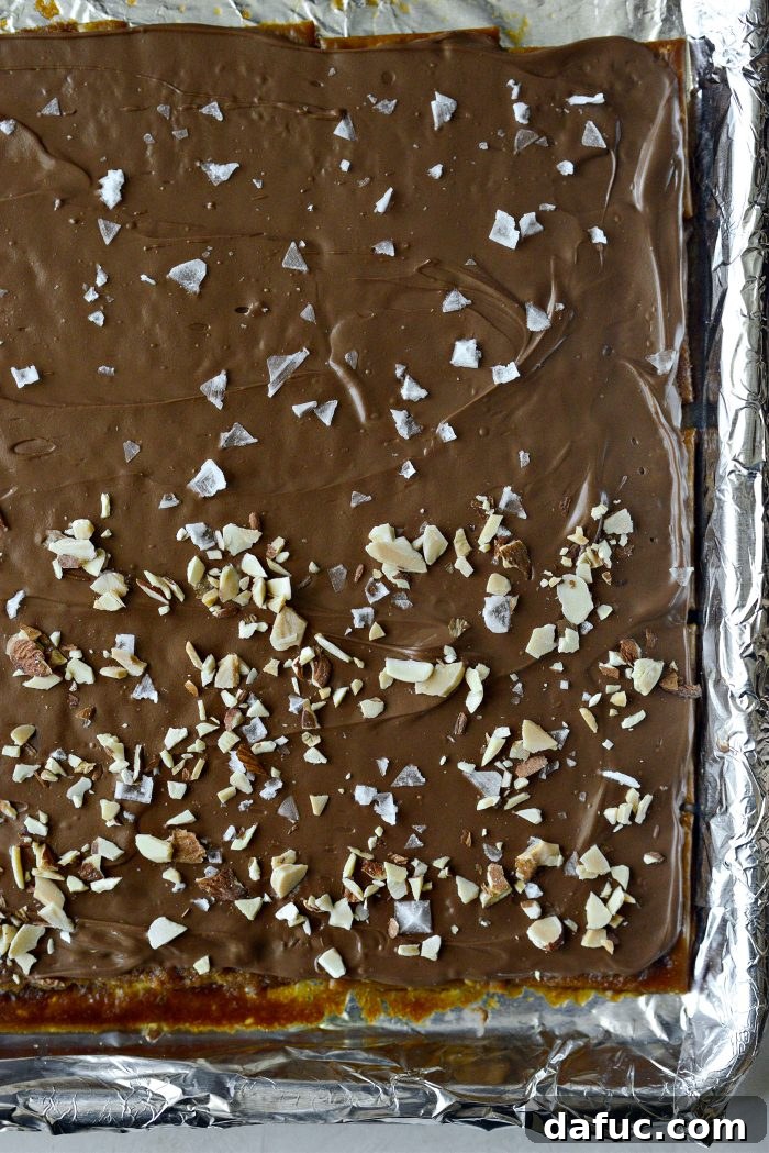 Finished Saltine Toffee with flaky sea salt and chopped toasted almonds sprinkled generously on top before the chocolate sets, adding texture and flavor.