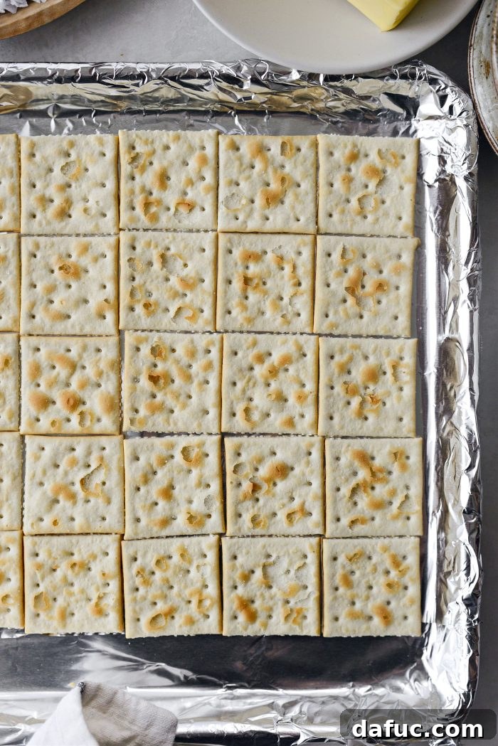 A baking sheet lined with aluminum foil, with 40 saltine crackers carefully arranged in a tight, even layer.