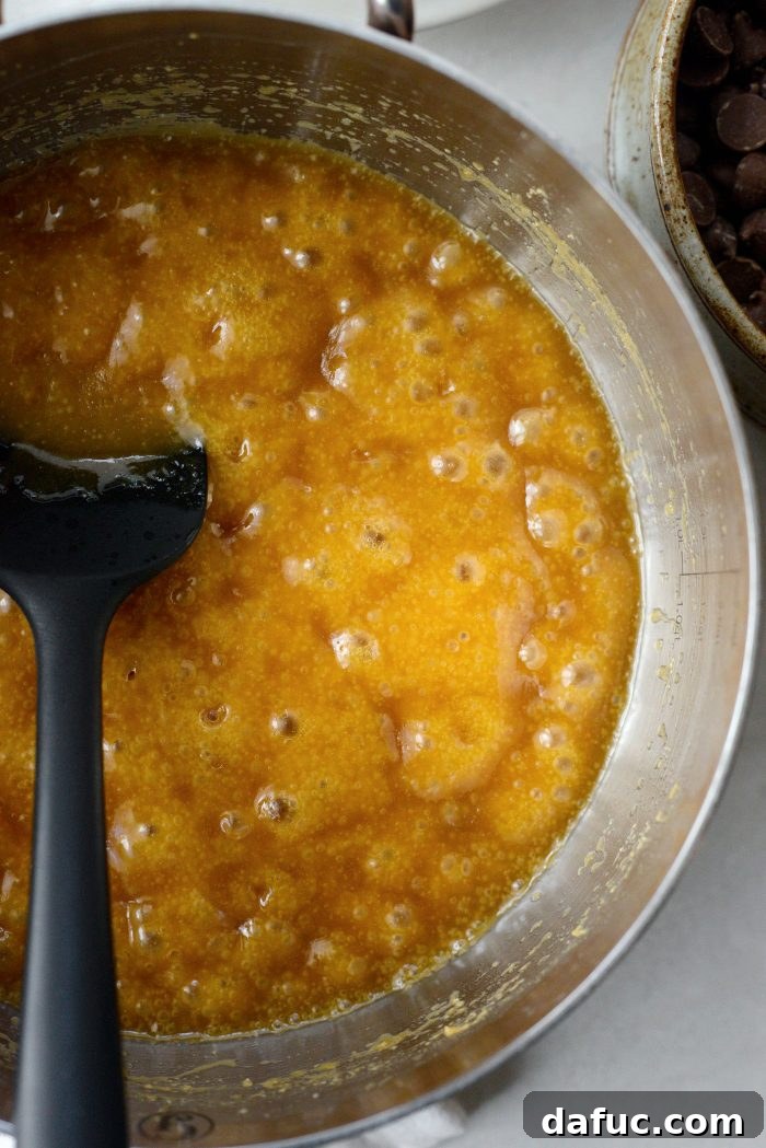 The butter and brown sugar mixture boiling vigorously in a saucepan, showing a rich caramel color and bubbly consistency, indicating the sugar has dissolved.