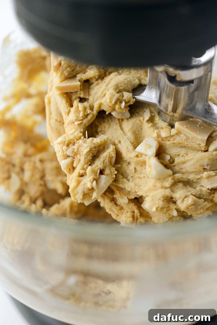 Gourmet White Chocolate Macadamia Nut Treasures 12 Mixing macadamia nuts and white chocolate into the cookie dough on low speed