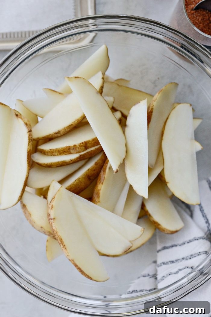 Crispy Seasoned Steak Fries 6 Adding potato wedges into a large mixing bowl for seasoning