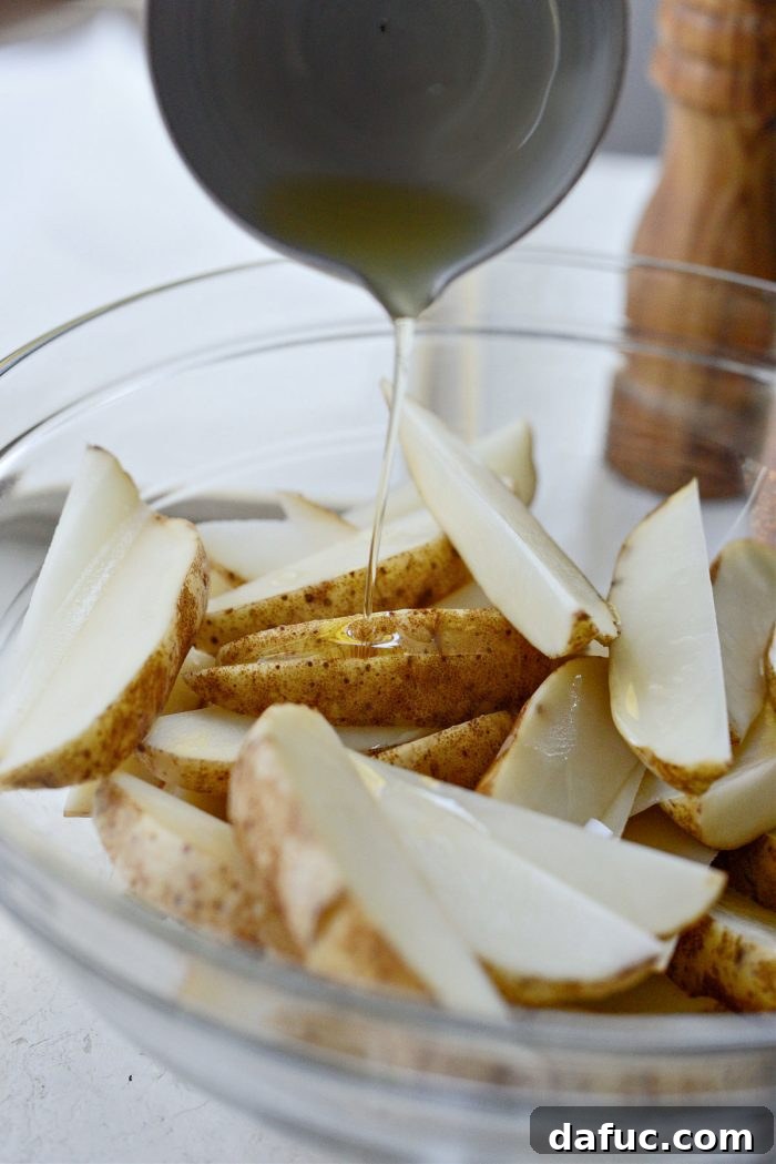 Crispy Seasoned Steak Fries 7 Drizzling avocado oil over potato wedges in a bowl