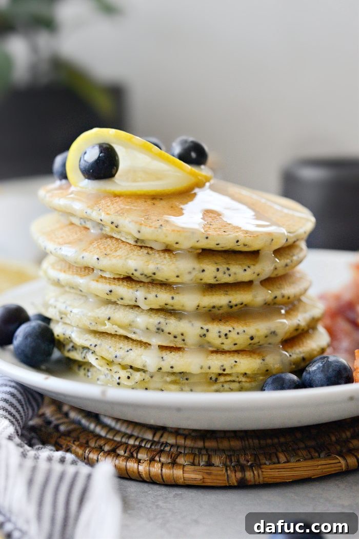Fluffy Lemon Poppy Seed Pancakes Stacked with Glaze and Berries