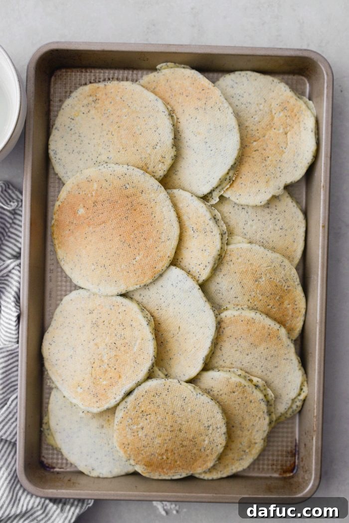 Transferring cooked pancakes to a baking sheet to keep warm