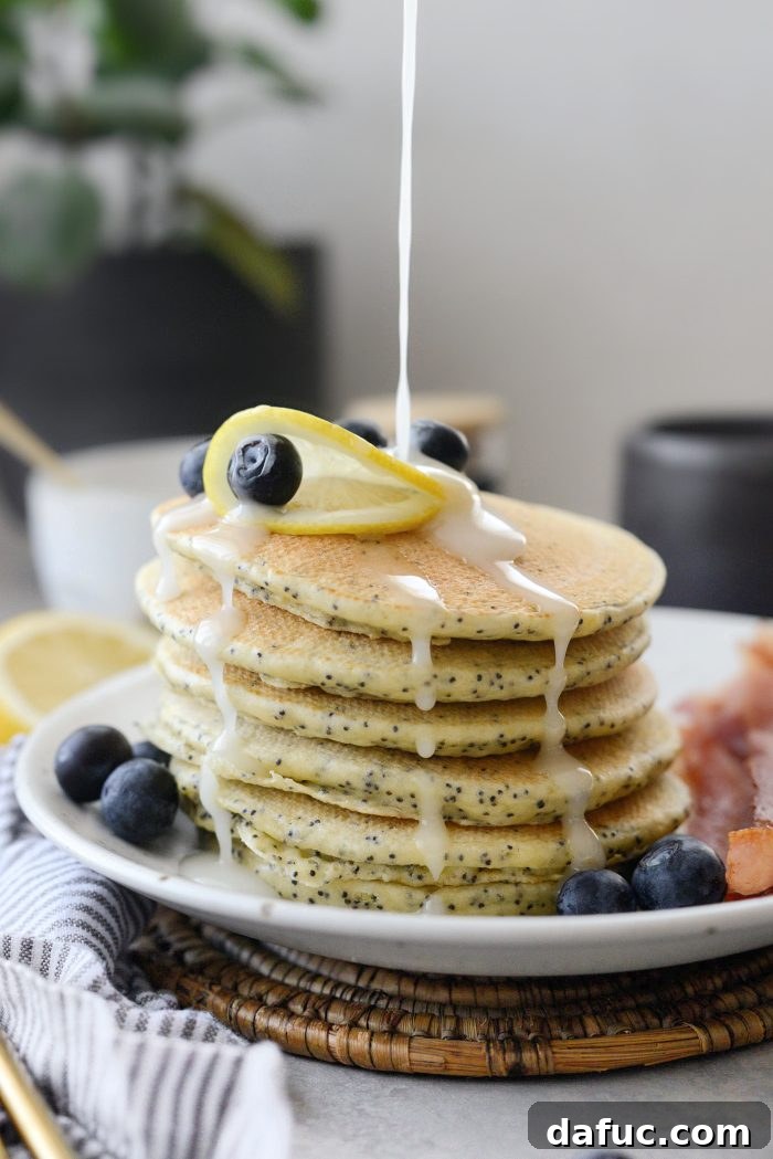 Drizzling lemon glaze over lemon poppy seed pancakes