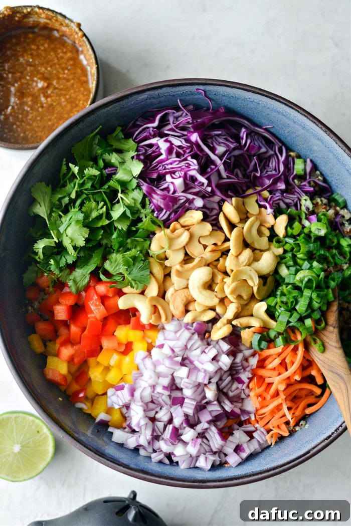 Vibrant Thai Quinoa Salad with Cashew Crunch 9 cabbage, cilantro, peppers, onion carrot, cashews and green onion in bowl with quinoa