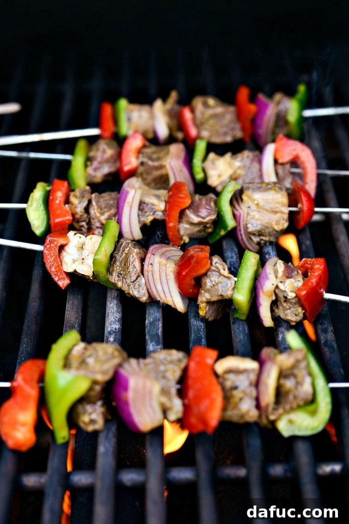 Grilled marinated steak kebabs cooking on a hot grill, showing smoky atmosphere