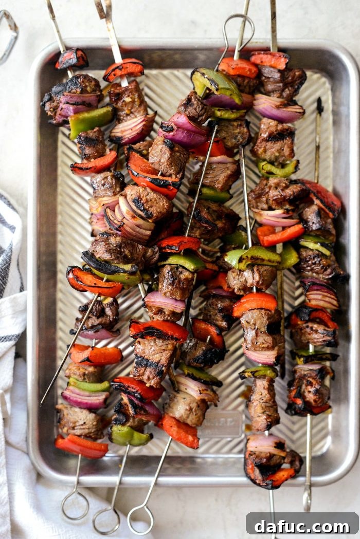 Cooked grilled marinated steak kebabs resting on a metal pan after removal from the grill