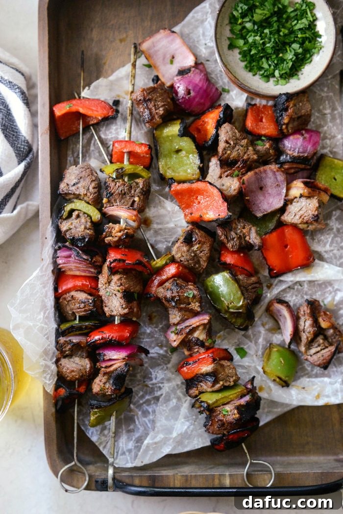 Close-up shot of grilled marinated steak kebabs both on and off the skewer, highlighting texture and juices