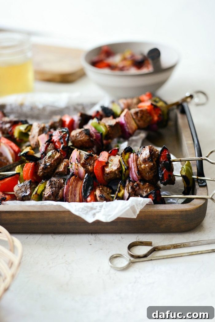 Close-up side view of grilled marinated steak kebabs on a wooden tray