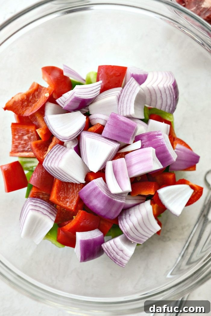 Large chunks of chopped bell peppers and red onion in a glass bowl