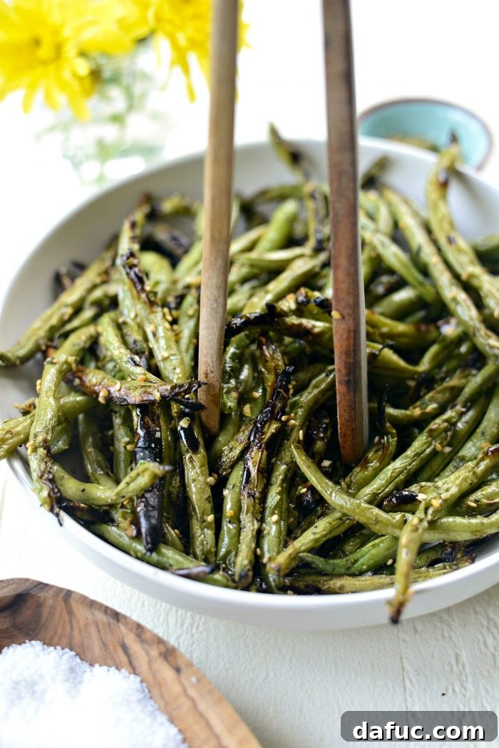 A vibrant bowl of grilled green beans, garnished and ready to be served, showcasing the perfect char.