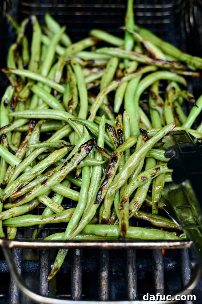 Perfectly grilled green beans inside a grill basket, showing a smoky char and tender texture.