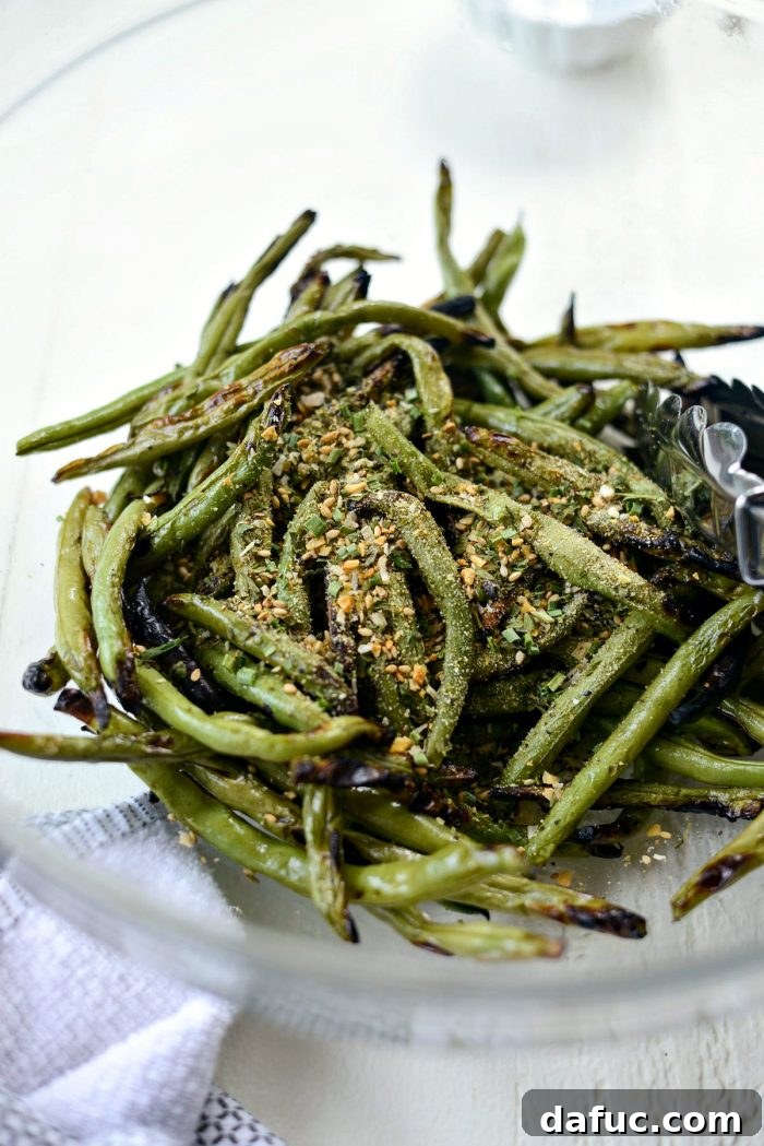 Grilled green beans in a bowl, having just been seasoned with garlic herb blend, ready to be tossed.