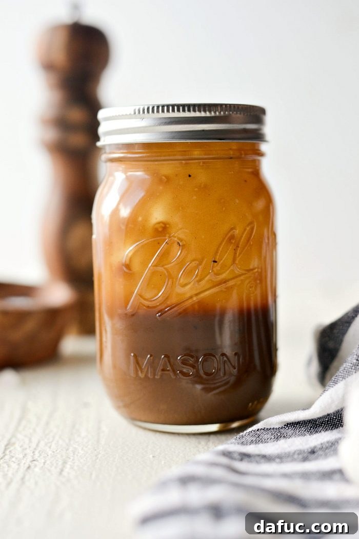 Signature Balsamic Vinaigrette 5 A hand vigorously shaking a glass mason jar filled with the components of balsamic vinaigrette, actively emulsifying the dressing to achieve a uniform consistency.