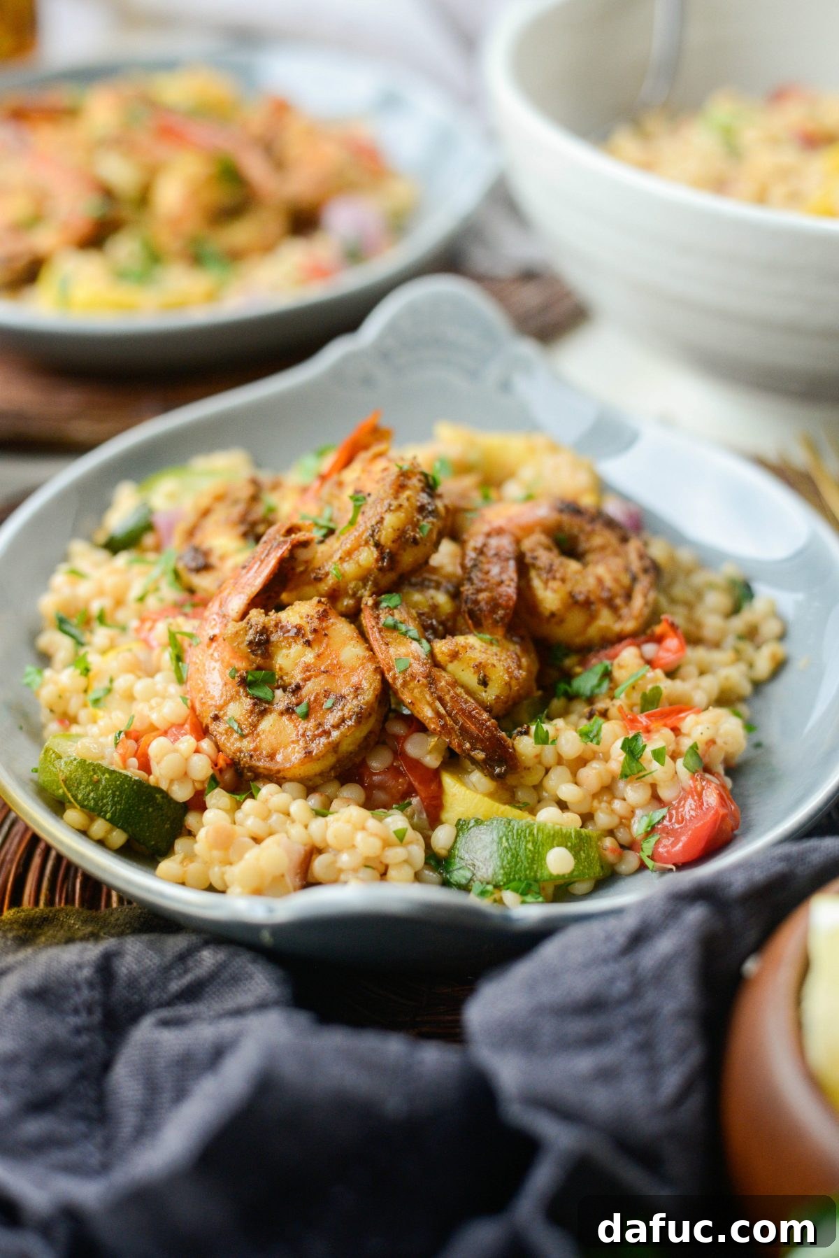 Aromatic North African Shrimp with Vibrant Summer Couscous 18 Plated North African Shrimp with Roasted Summer Vegetable Couscous, garnished.