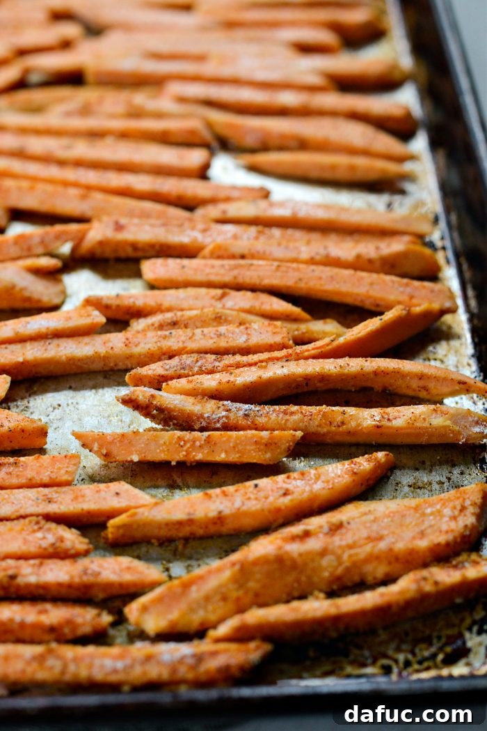 Coated sweet potato fries arranged in a single, even layer on a hot, preheated baking sheet