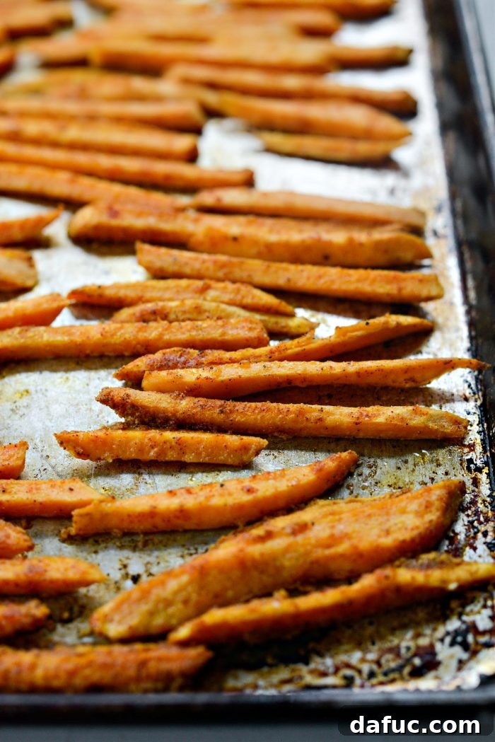 Sweet potato fries being carefully turned after 15 minutes of baking