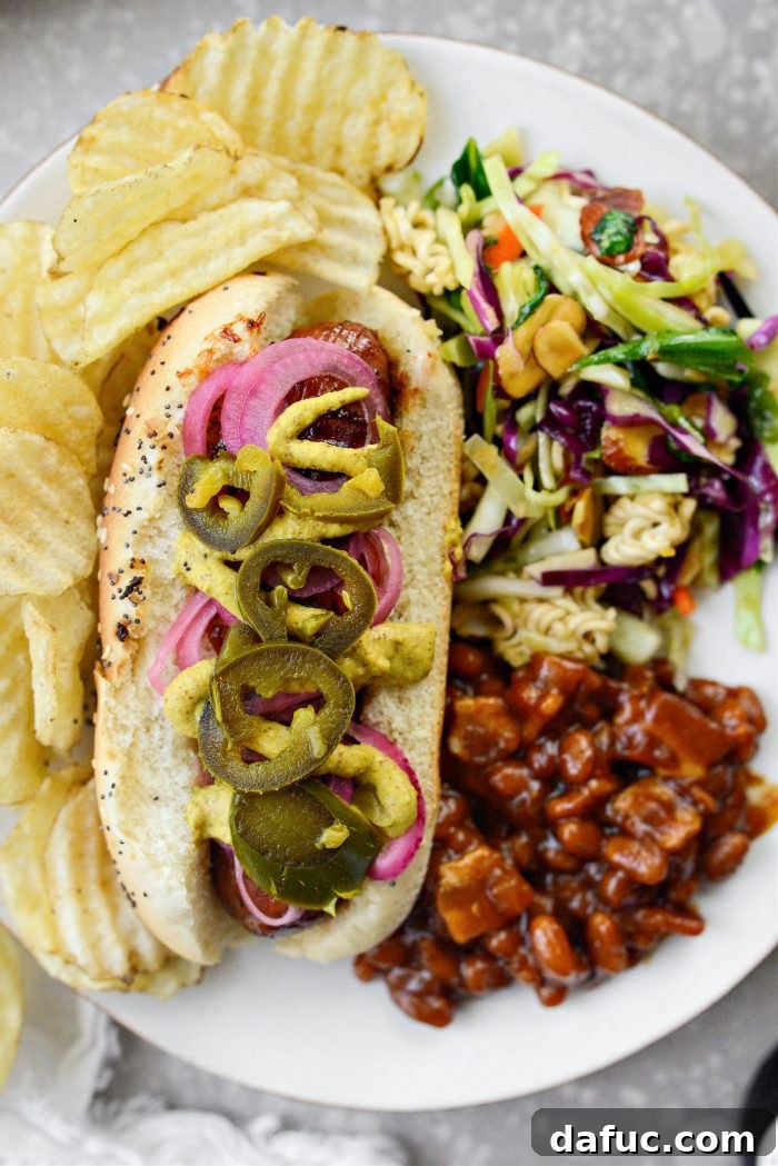 Smoky BBQ Glazed Chicken Brats 3 Close-up of a plate with Grilled BBQ Sauce Chicken Brats, complete with pickled red onions and mustard, ready to be enjoyed.