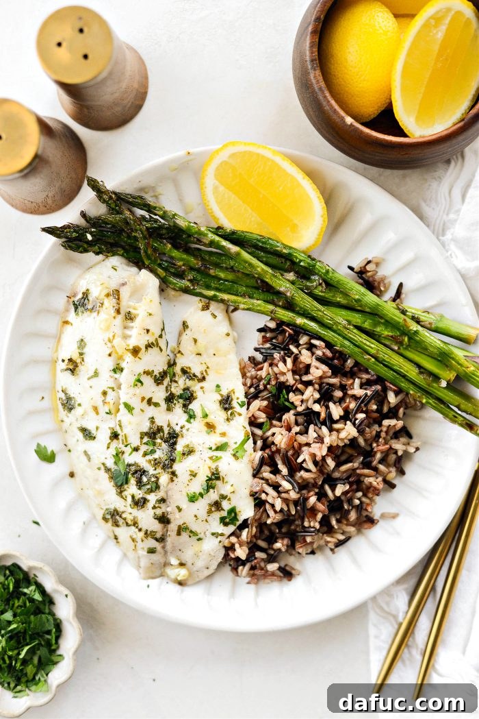 Perfectly cooked Sheet Pan Lemon Garlic Tilapia with Asparagus, garnished