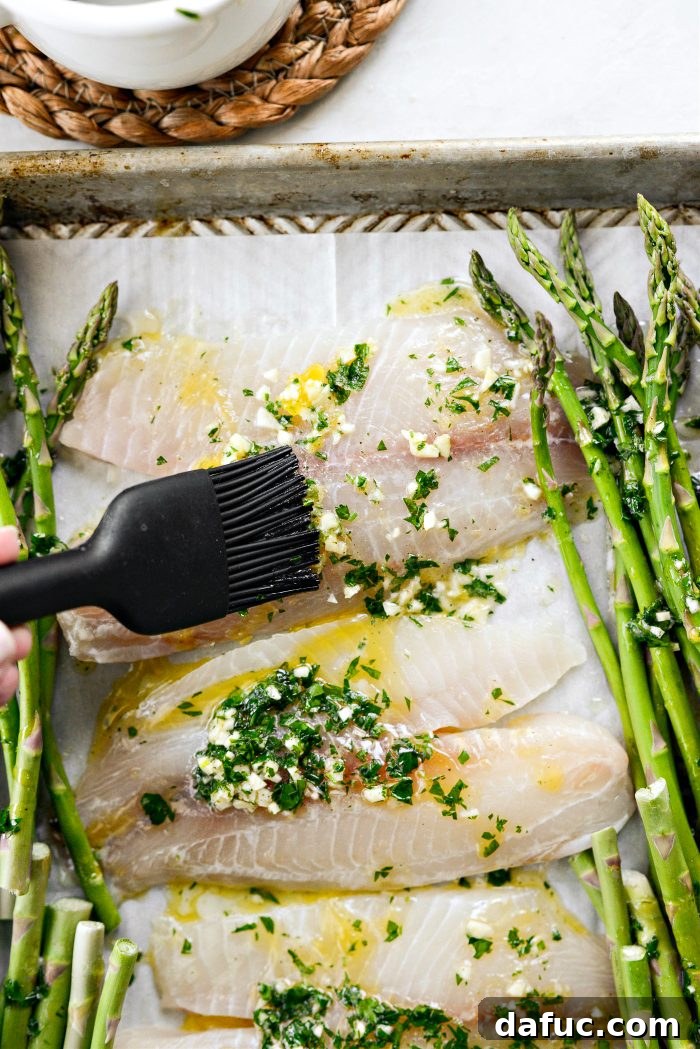 Brushing lemon garlic butter mixture over fish fillets for even coating